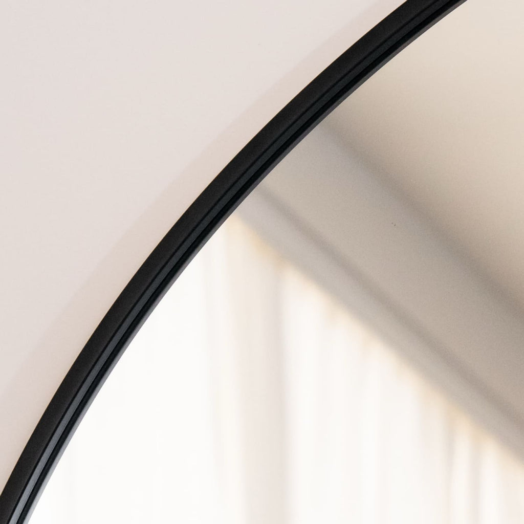 Close-up of a curved mirror with a black frame on a white background