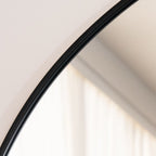 Close-up of a curved mirror with a black frame on a white background