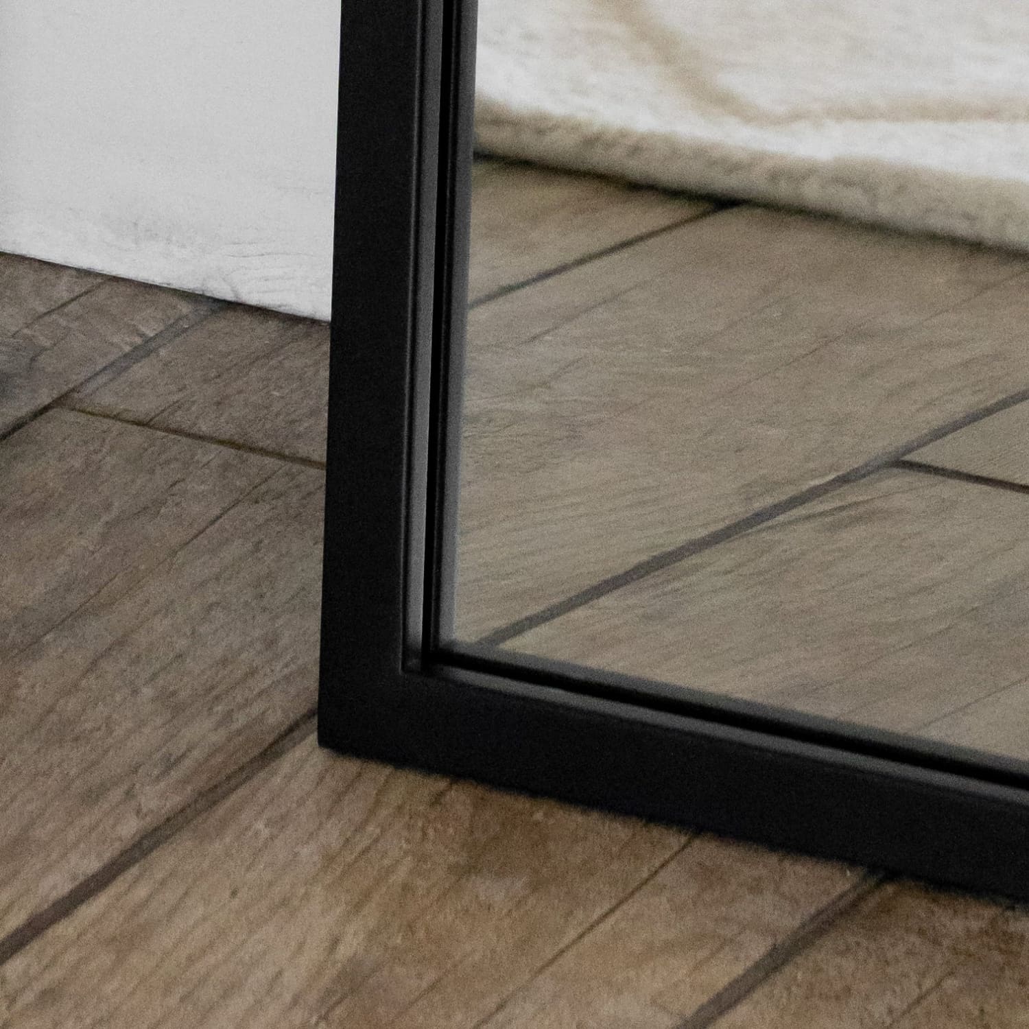 Close-up of a black-framed mirror on a wooden floor