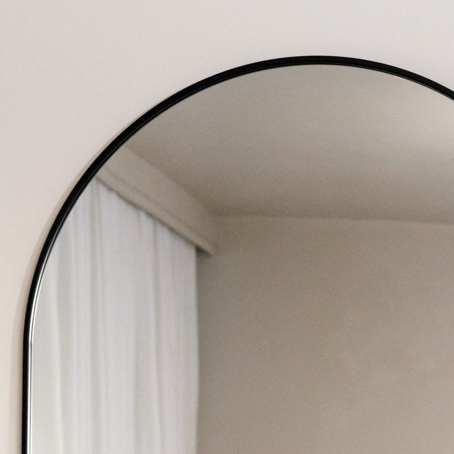 Round mirror with black frame on a white wall
