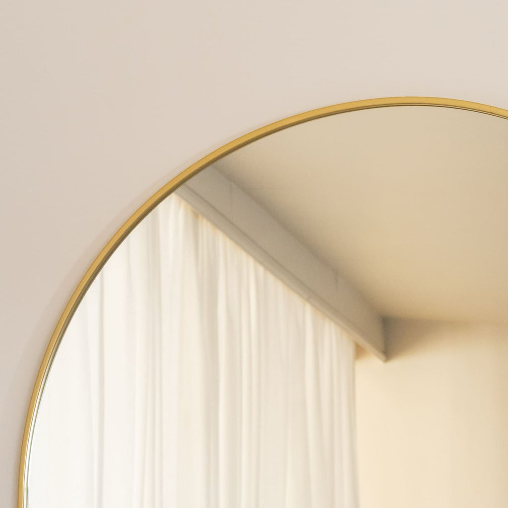 Round mirror with a gold frame on a wall