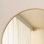 Round mirror with a gold frame on a wall