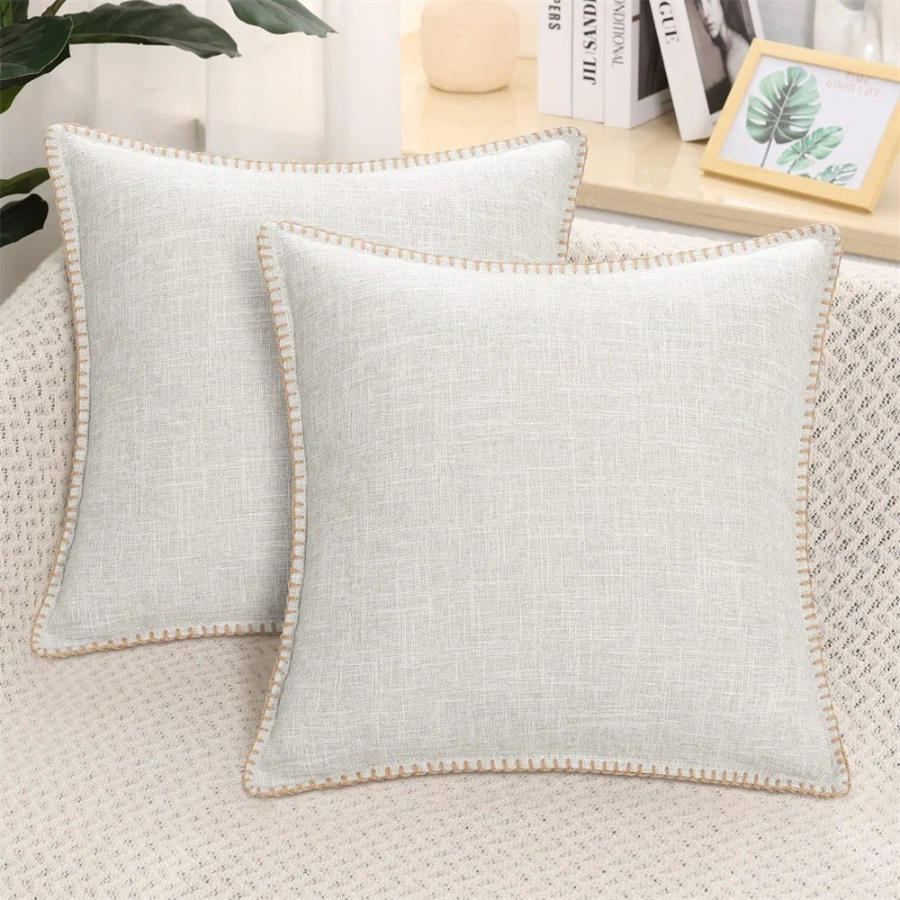 Two light gray velvet cushion covers with a solid pattern and decorative trim, displayed on a neutral background.