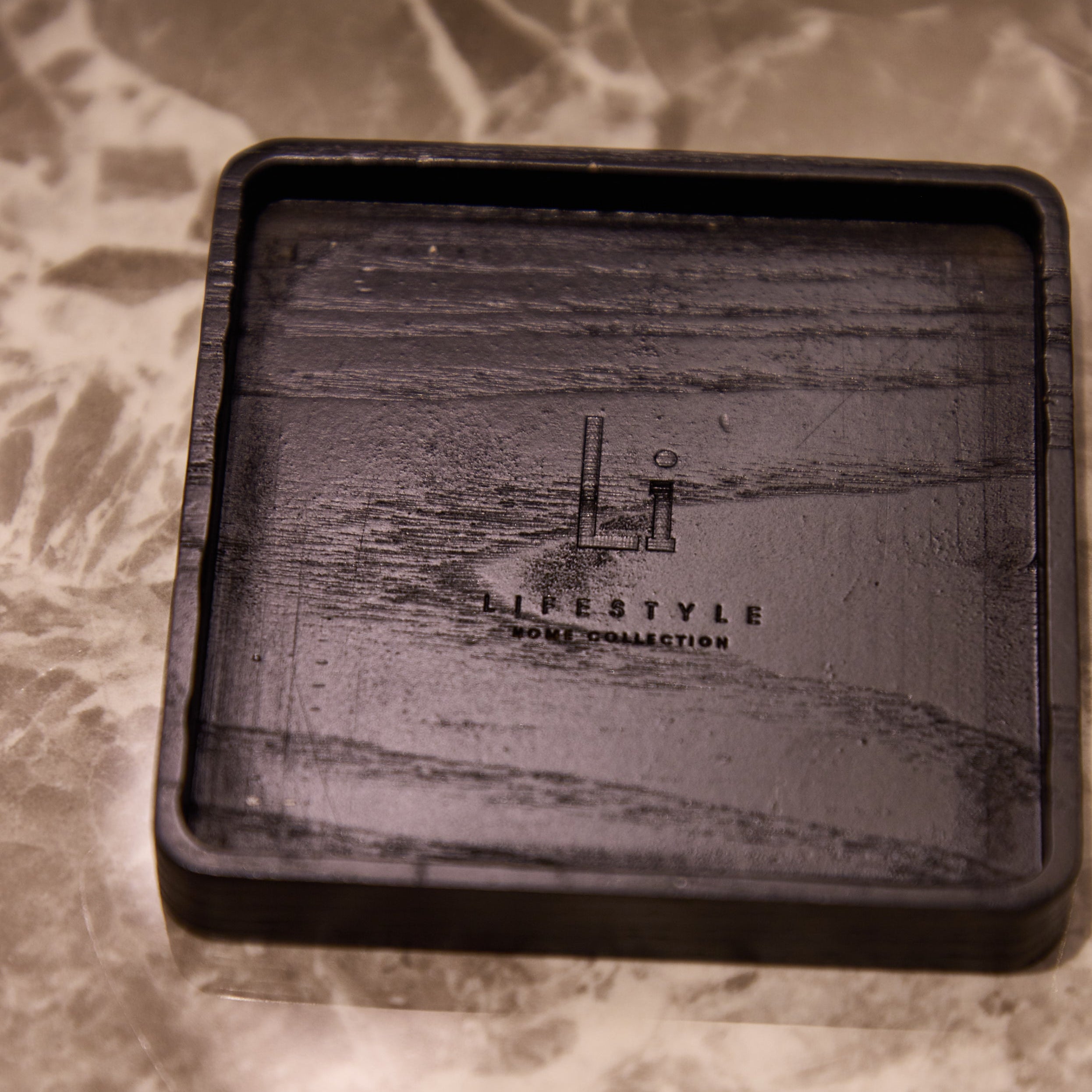 Black rectangular tray with engraved design on a marble surface