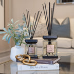 Two diffusers on books with a plant and decorative items on a coffee table in a living room.