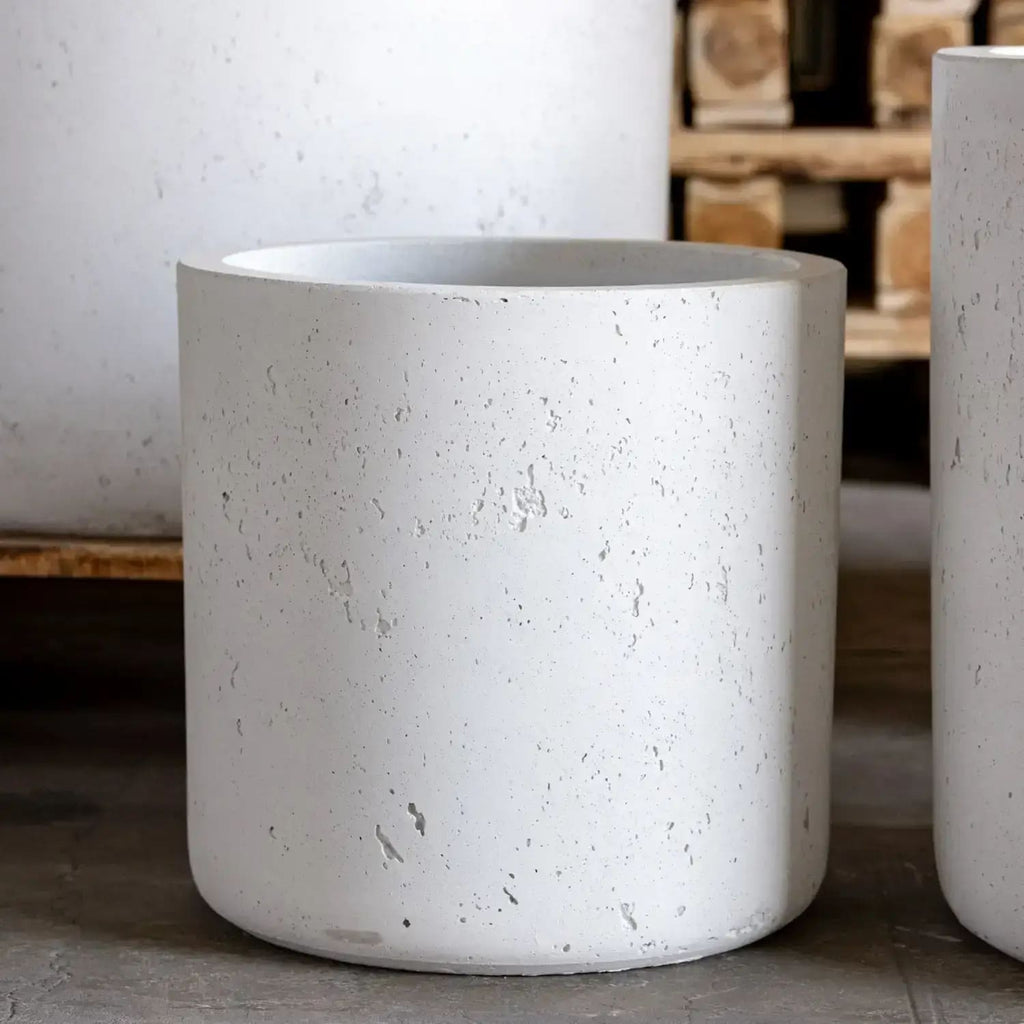 White concrete planters on a wooden floor with a blurred background