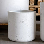 White concrete planters on a wooden floor with a blurred background