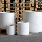 Set of white concrete planters in front of wooden pallets