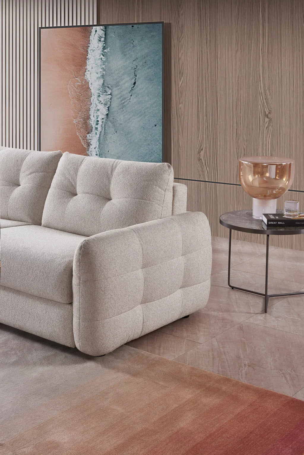 Modern living room with a beige sofa, small round table, and abstract artwork on a wooden wall.
