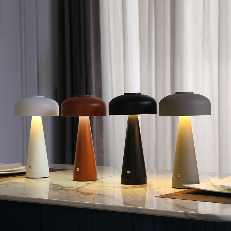 Four different colored table lamps on a marble surface with curtains in the background.