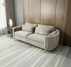Beige sofa with cushions in a room with wooden walls and a side table.