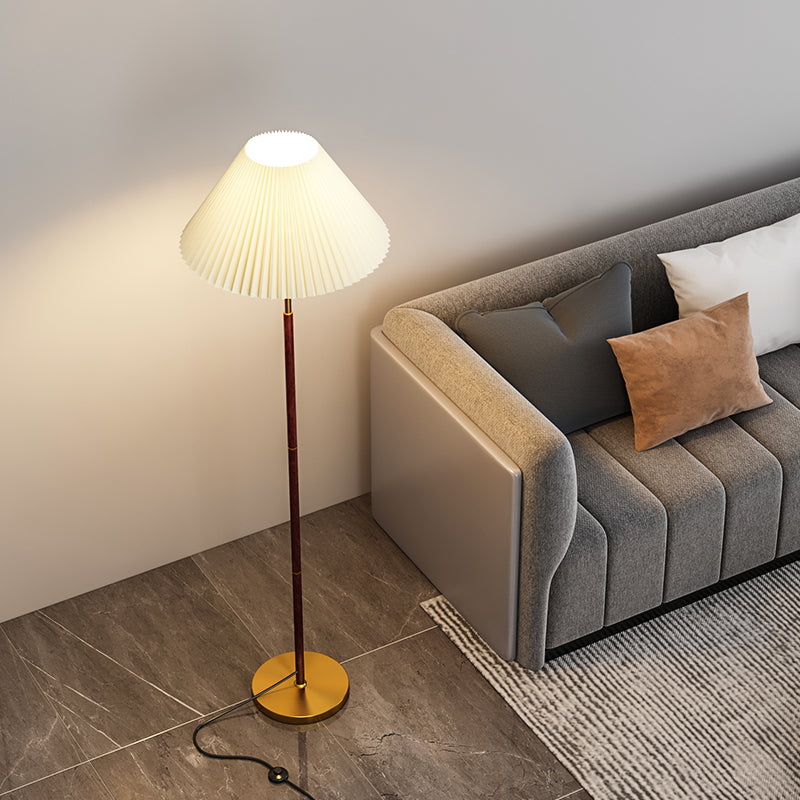 Modern floor lamp next to a gray sofa with cushions in a living room setting.