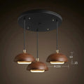 Modern pendant light fixture with three brown lampshades on a dark background