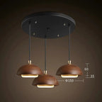 Modern pendant light fixture with three brown lampshades on a dark background