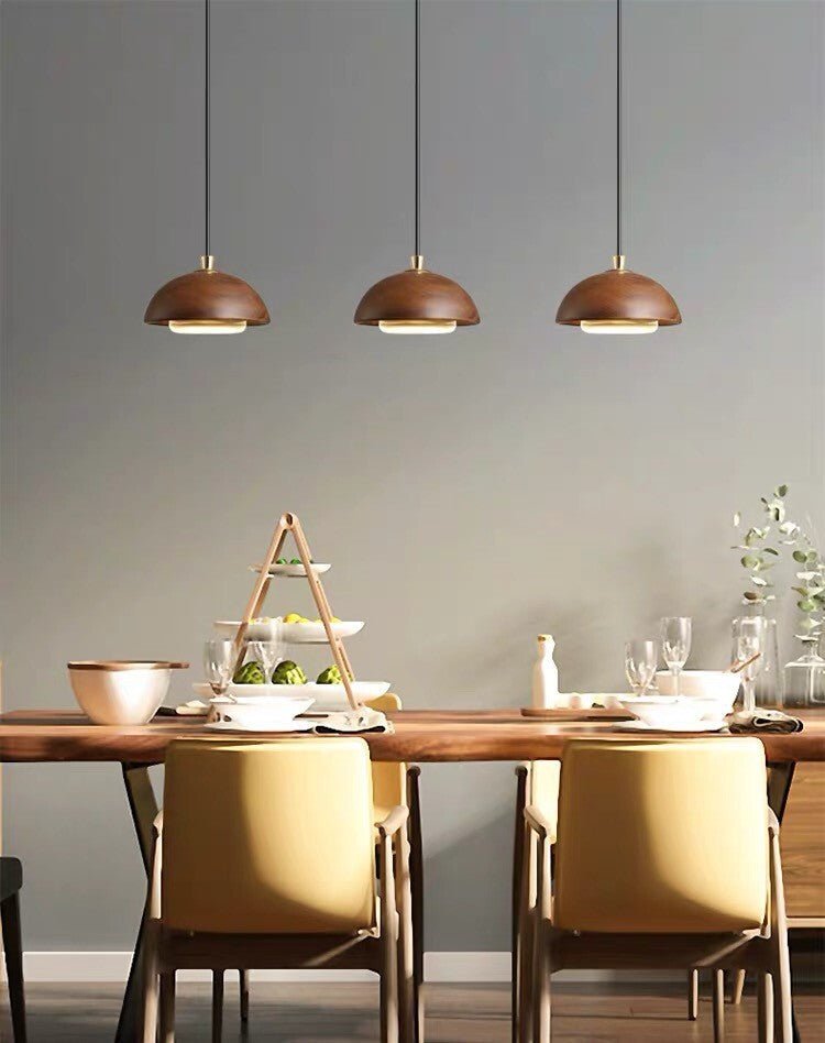 Dining area with wooden table, chairs, and pendant lights against a gray wall.