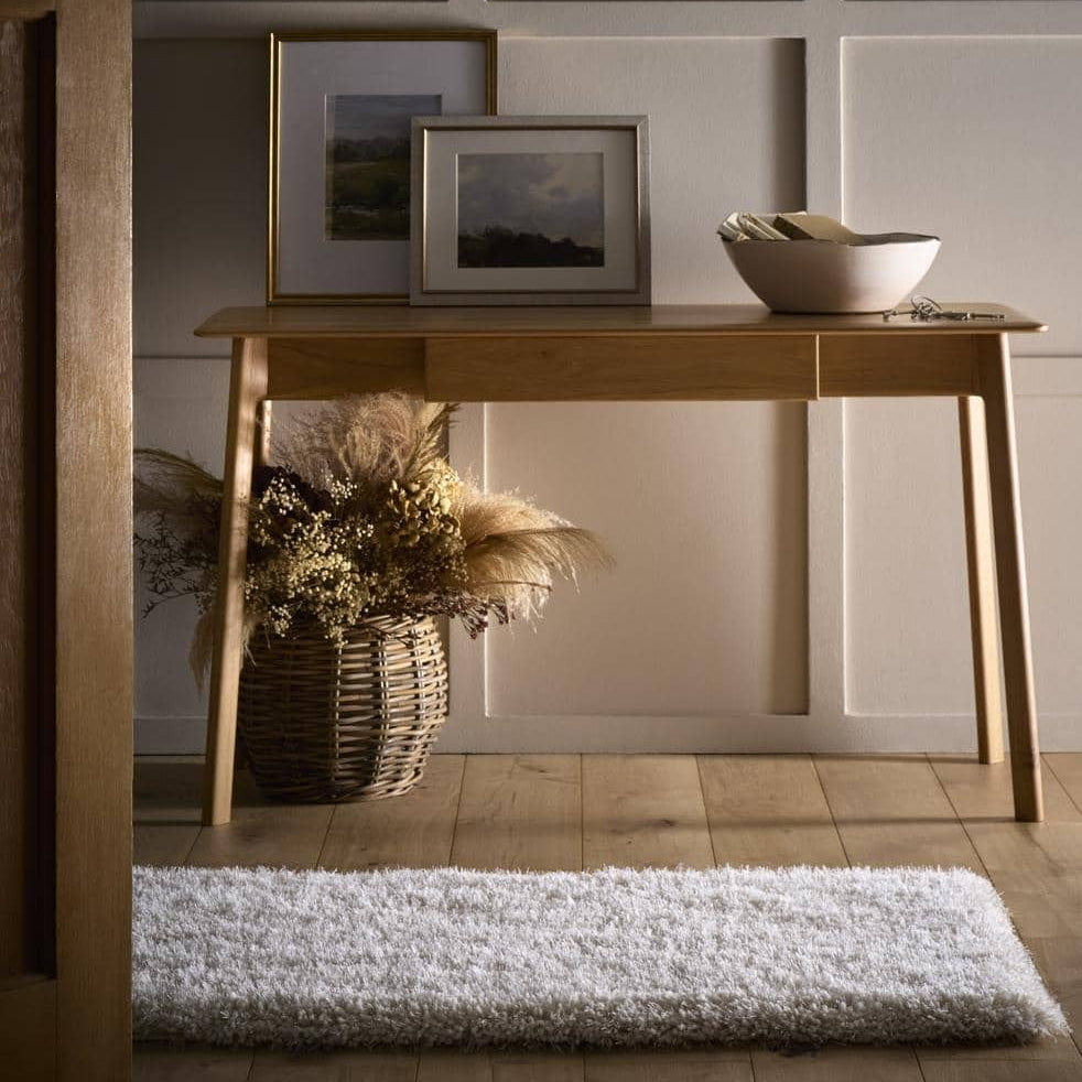 Wooden console table with decorative items against a paneled wall.