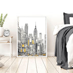 Cityscape artwork in a white frame on a wall above a bed with gray bedding.