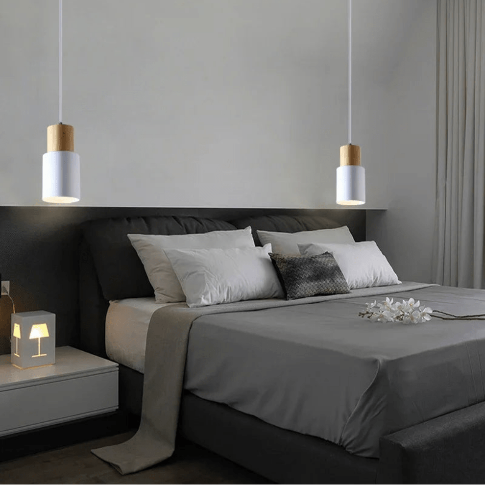Modern bedroom with gray bedding, white pillows, and pendant lights.