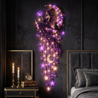 A split comparison showing a decorative wall hanging in two states: DAY on the left and NIGHT on the right. The product is a witch-themed crescent moon wall decor featuring a seated witch in a purple gown, a black cat, hanging purple star and teardrop charms, and warm LED star and moon lights.