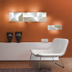 Modern interior with a white chair, decorative wall art, and books against an orange wall.