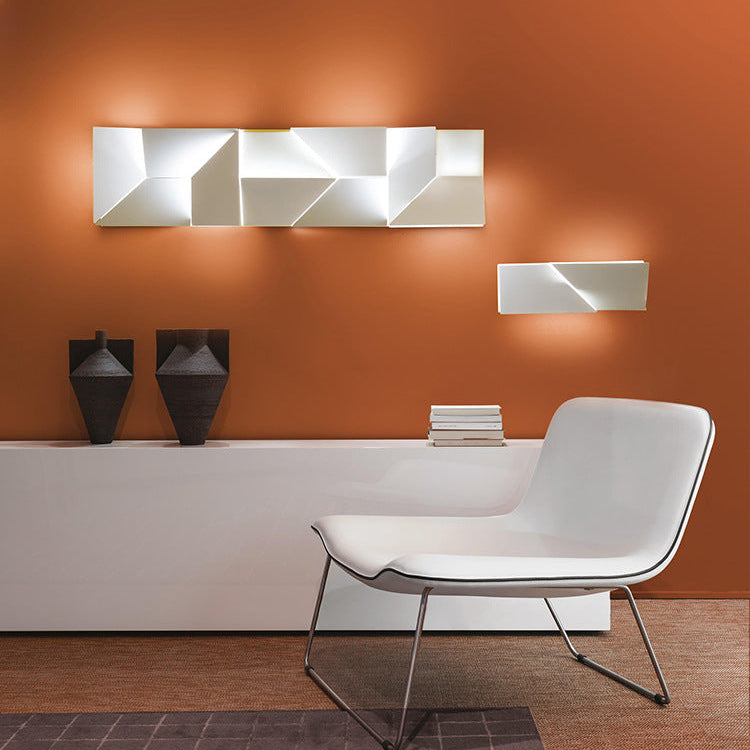 Modern interior with a white chair, decorative wall art, and books against an orange wall.