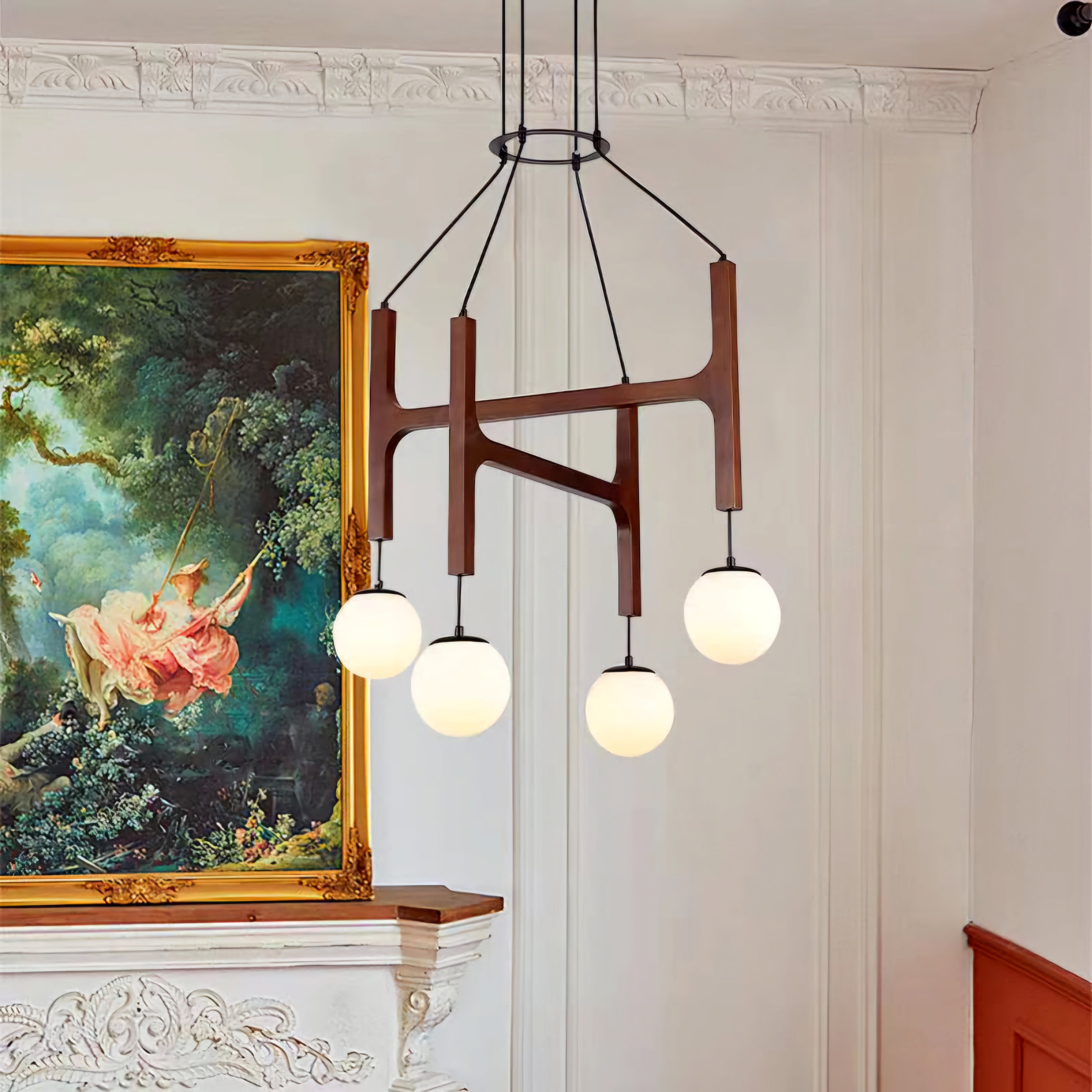 Modern chandelier with three round lights in a room with decorative wall art.