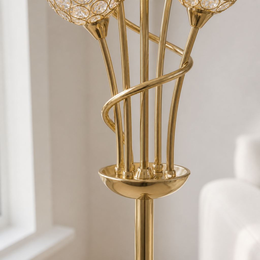 Close-up of a polished gold floor lamp with multiple slender stems, a spiral accent, a round base, and clear crystal-like globe shades in a softly lit interior setting.
