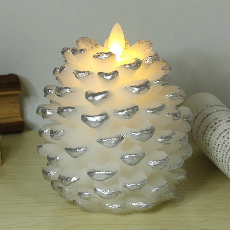 Pine cone-shaped candle with a lit flame on a wooden surface.