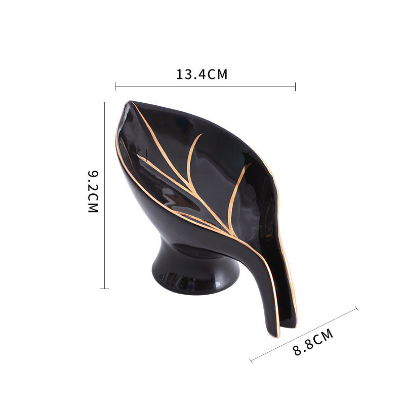 Black leaf-shaped object with gold accents and measurements on a white background