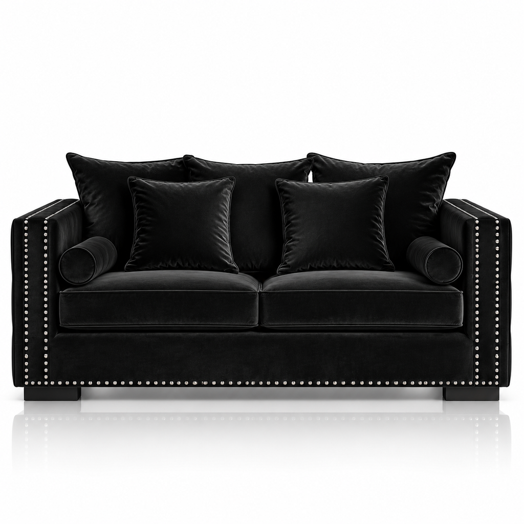 A black velvet loveseat sofa with matching throw pillows, featuring silver nailhead trim along the armrests and front edge, set against a clean white background with a subtle reflection below.
