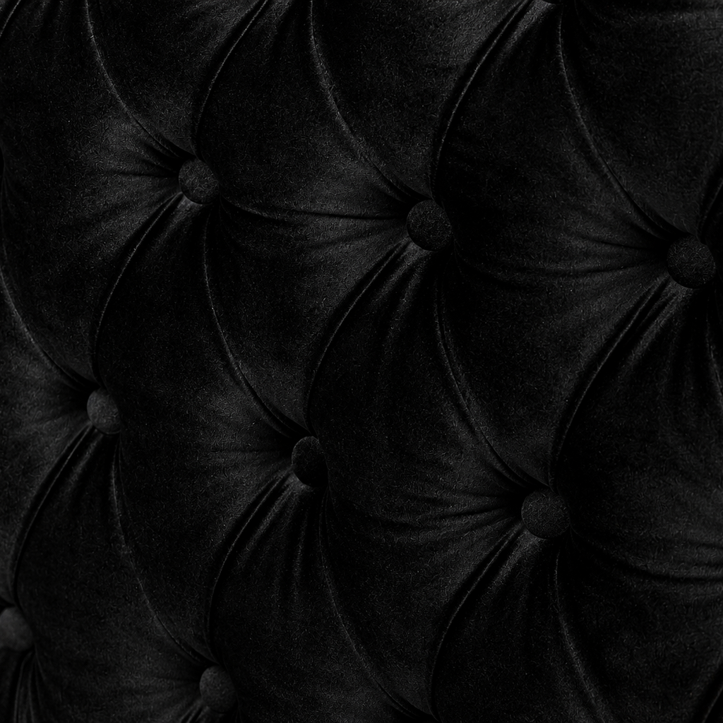 Close-up of a black tufted velvet upholstery surface with deep button tufting and a soft sheen.
