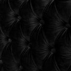 Close-up of a black tufted velvet upholstery surface with deep button tufting and a soft sheen.