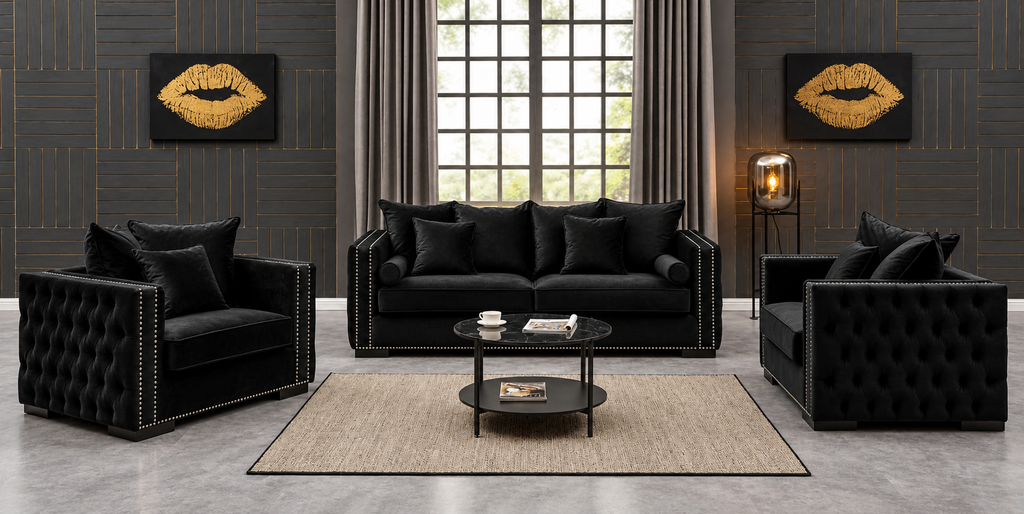 A luxury black tufted velvet living room furniture set, including a three-seater sofa, two armchairs, and a round coffee table, arranged on a beige rug in a modern styled room with dark wood-paneled walls and gold lip art prints.