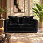 A black velvet loveseat sofa with matching throw pillows and nailhead trim, styled in a modern living room setting with plants, a rug, and wall art.