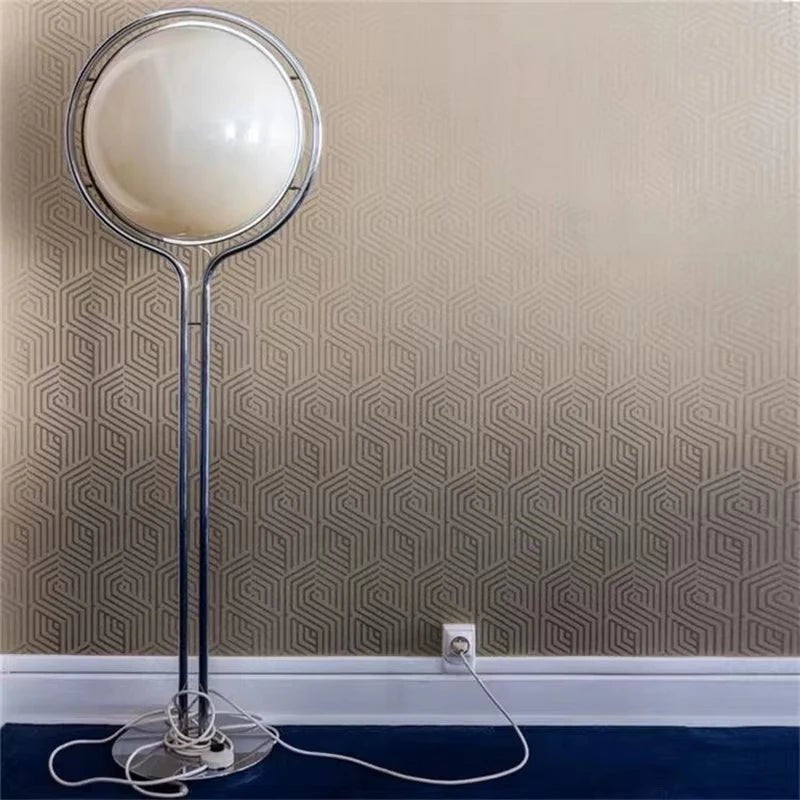 Floor lamp with a round white shade against a patterned wall.