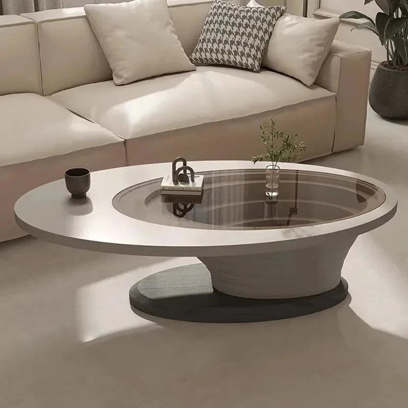 An oval-shaped luxury coffee table made of wood-based panels with a minimalist design, placed in a living room setting.