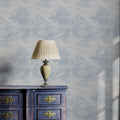 Decorative lamp on a wooden cabinet with floral wallpaper in the background