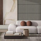 Modern living room with a white sofa, wooden coffee table, and abstract wall art.