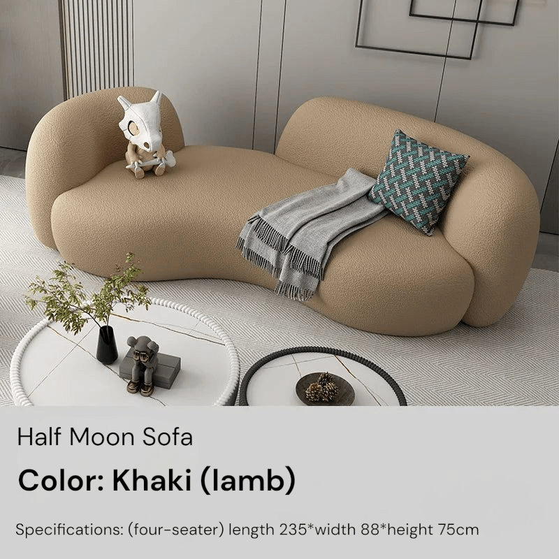 Khaki half moon sofa in a modern living room setting with a small table and decorative items.
