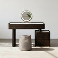 Modern dark wood console table with a round mirror and a small stool on a neutral background