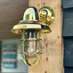 Gold outdoor wall light fixture on a wooden surface