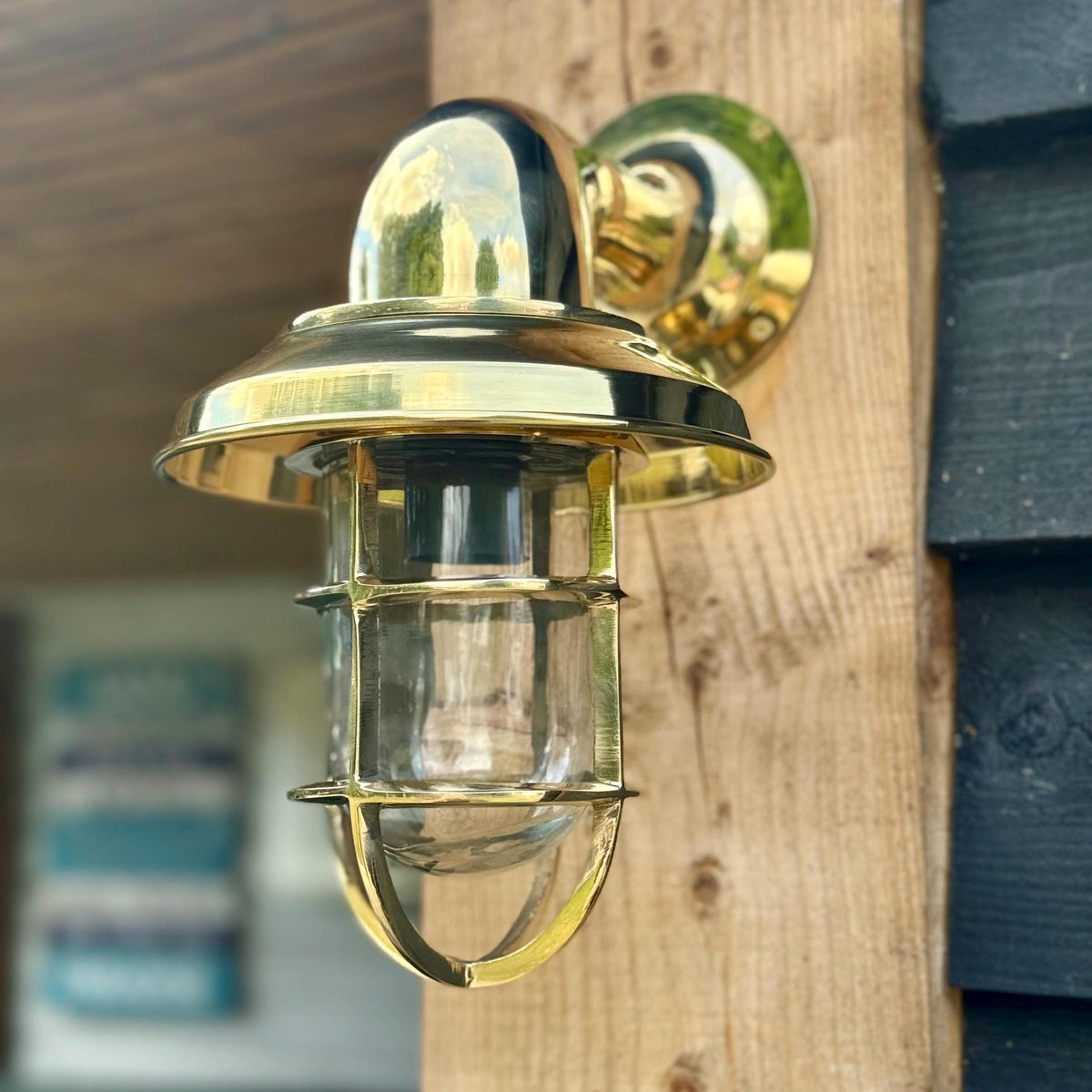 Gold outdoor wall light fixture on a wooden surface