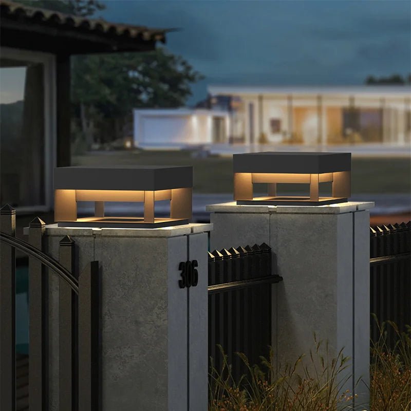 Two hexagonal outdoor lights on concrete pillars with a house in the background.