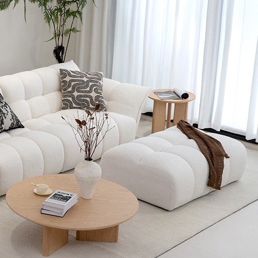 Modern living room with a white sofa, ottoman, and wooden coffee table.