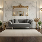 Modern living room with a gray sofa, decorative mirror, and plants.