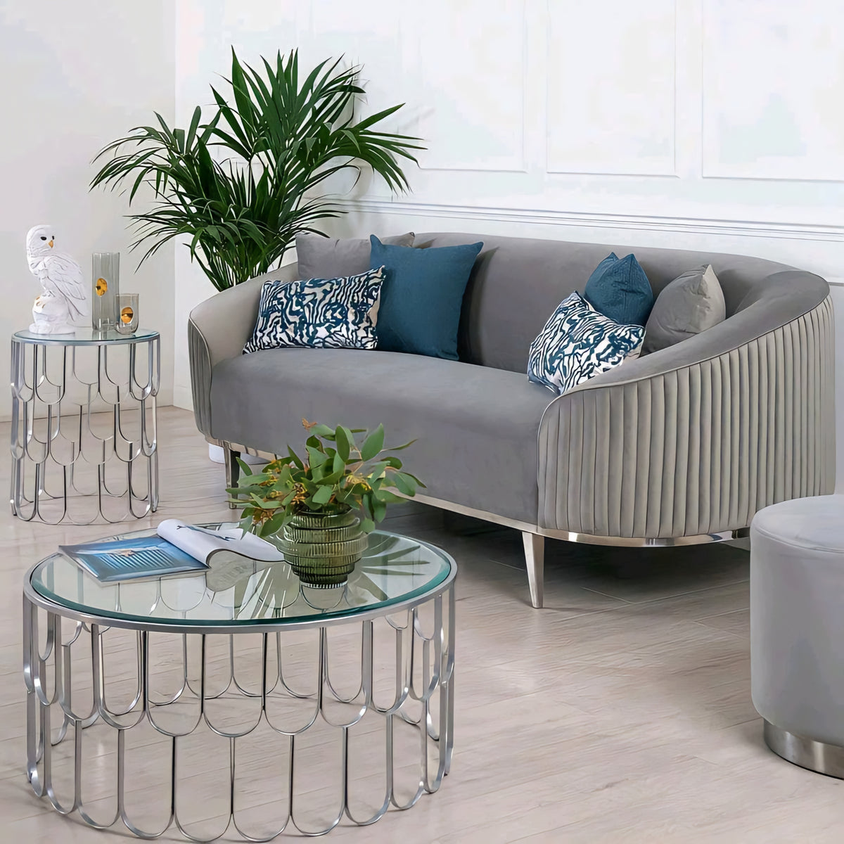 Modern living room with a gray sofa, glass coffee table, and decorative plants.