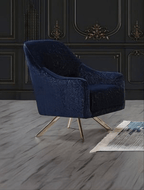 Blue velvet armchair with gold legs in a room with dark paneled walls.