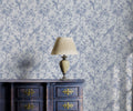 Decorative lamp on a wooden cabinet with floral wallpaper in the background