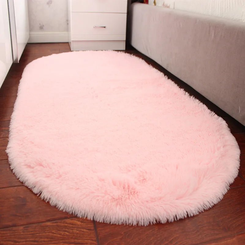 Pink round rug on a wooden floor in a room with white furniture.