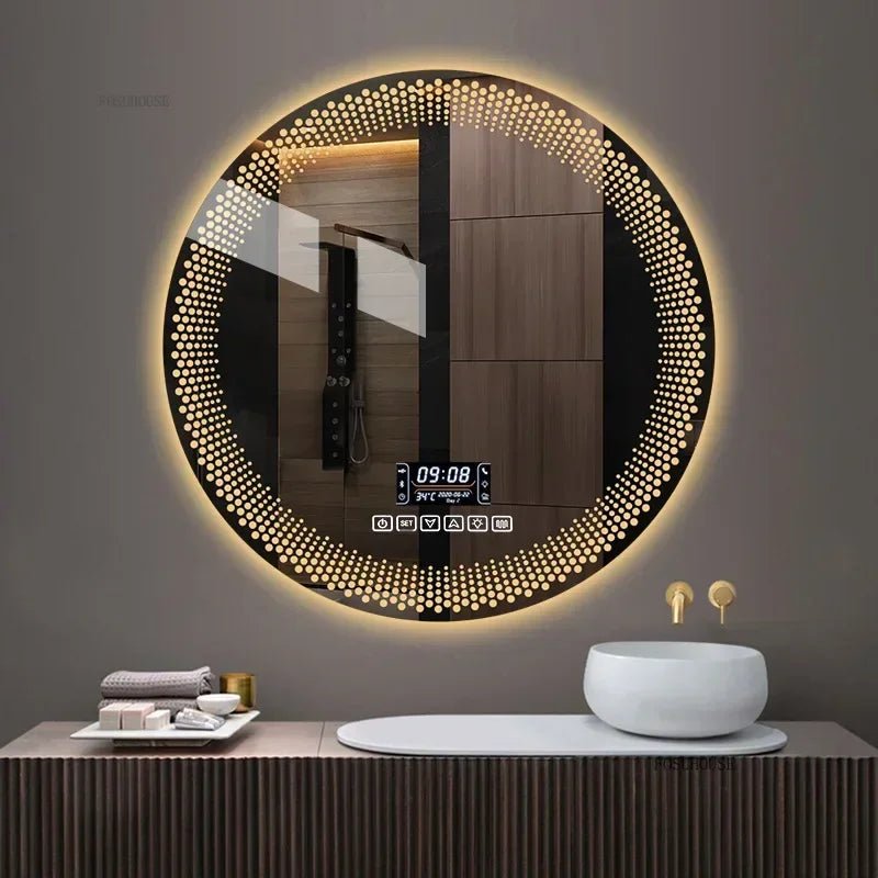 A round LED bathroom mirror with a silver aluminum frame, featuring a digital display at the bottom and illuminated with multicolored lights, mounted on a wall above a white sink.